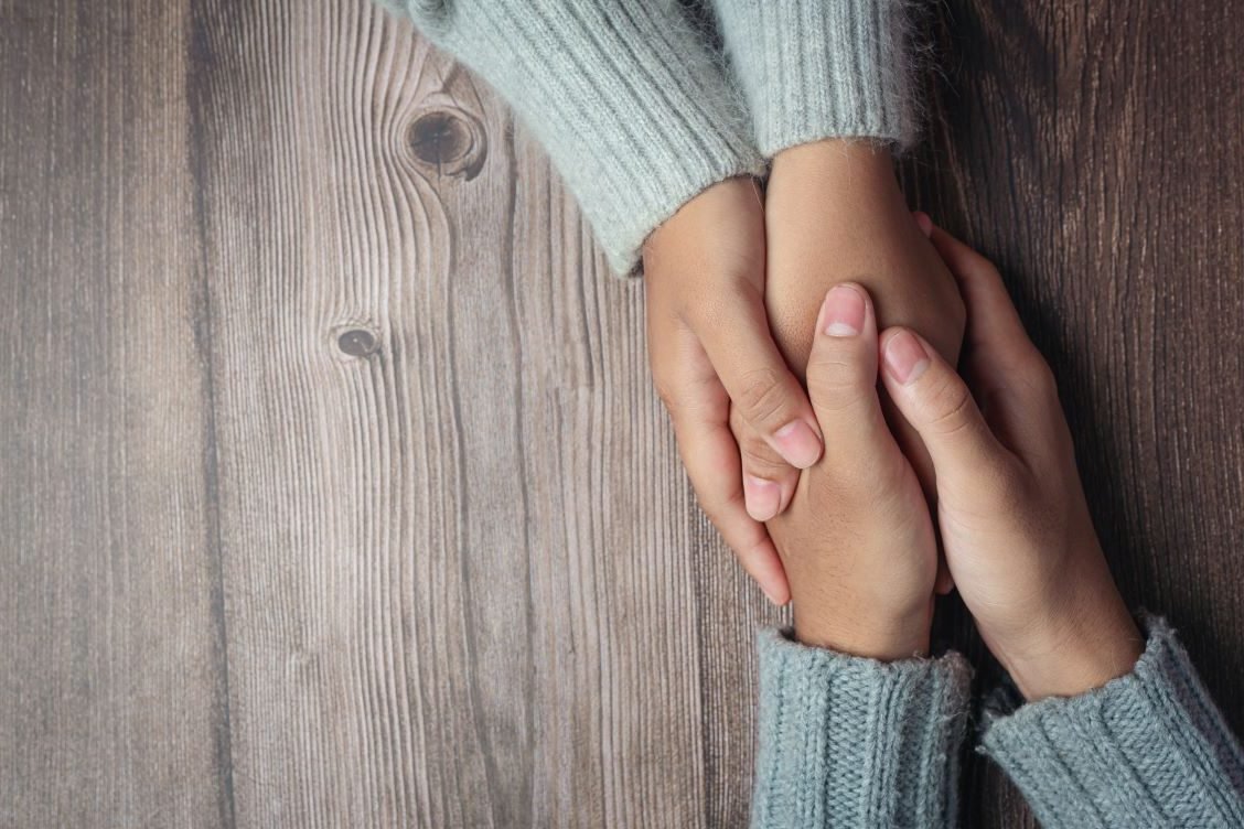 two people holding hands together with love warmth wooden table rotated - Become a volunteer
